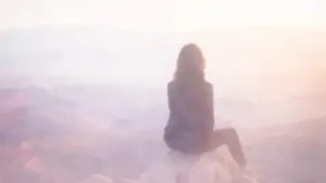 霧がかった幻想的な山頂で、一人の女性が静かに景色を眺める後ろ姿。内向型が自分らしくウェルビーイングを追求するイメージ。